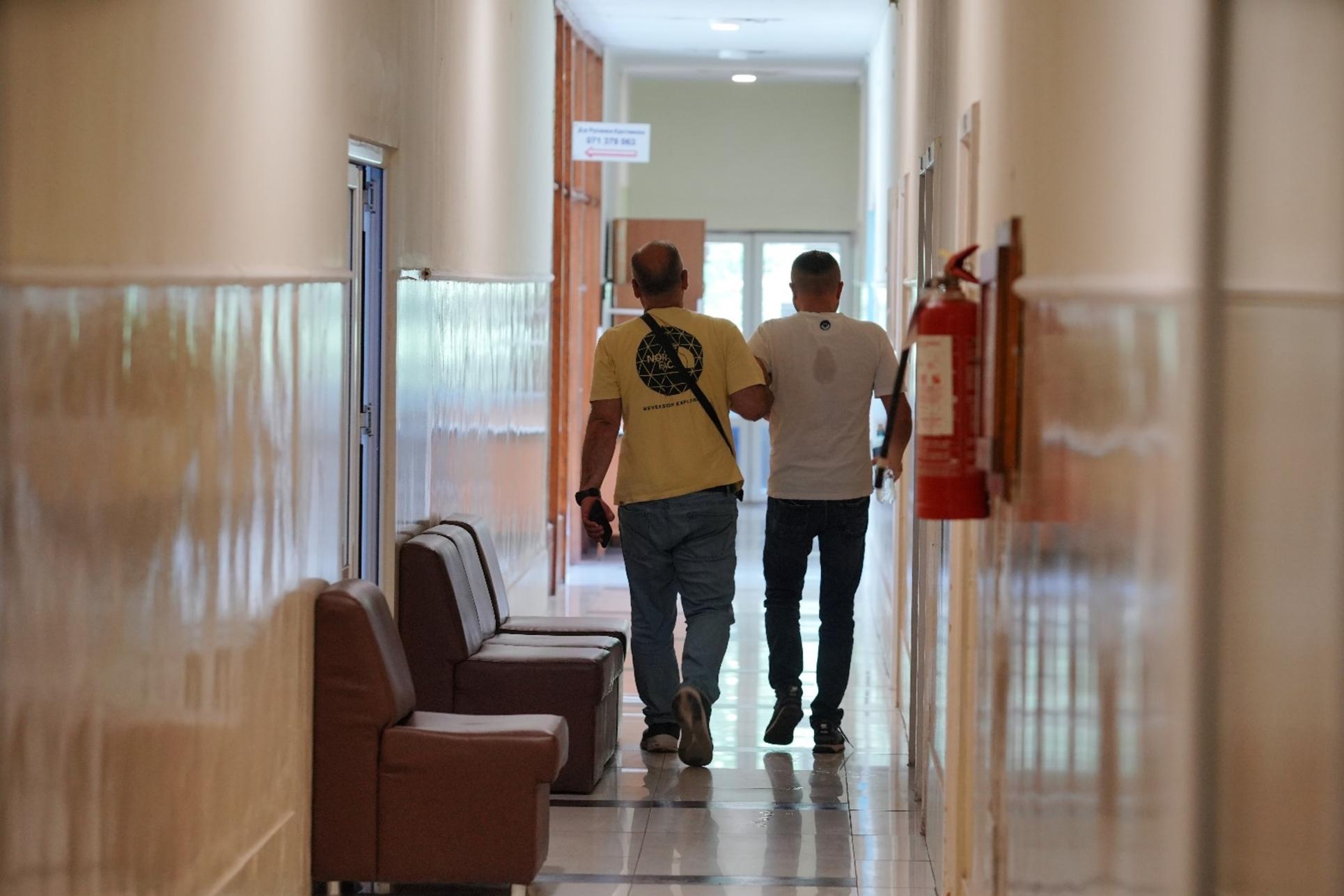 Back view of two individuals walking side by side in a clinic corridor