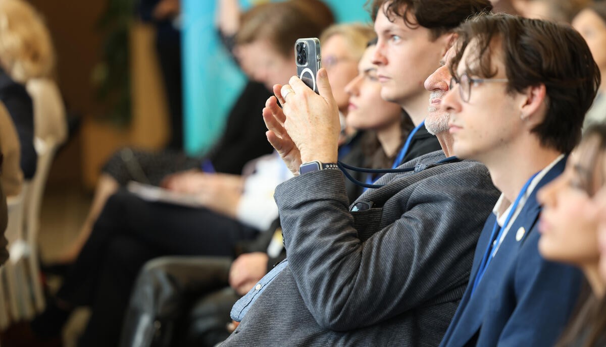 RC75 PHOTO GALLERY “Participants attentively watching and taking photos during a session at a conference or meeting