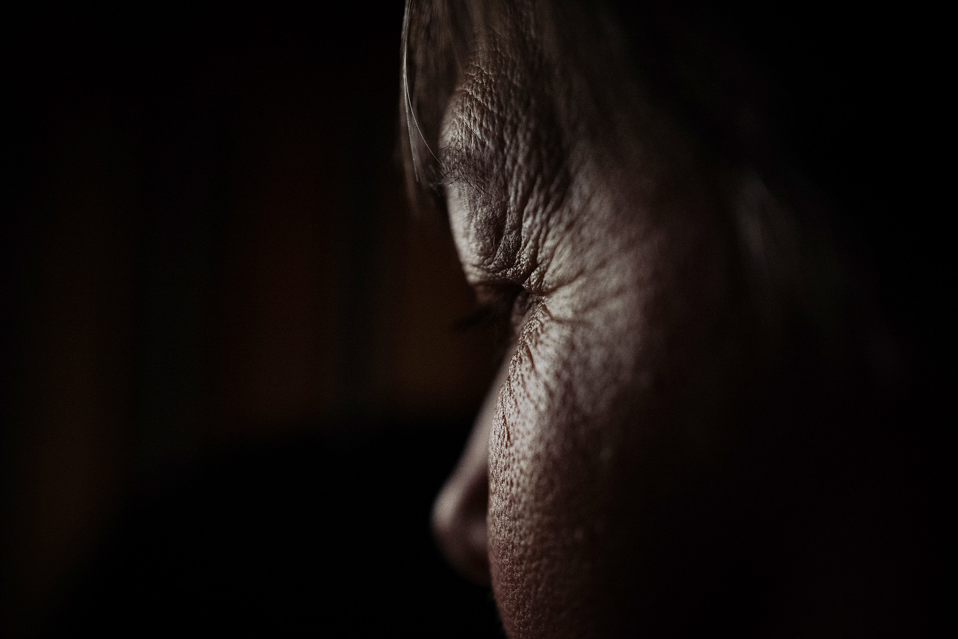 Profil du visage d'une femme, en silhouette et dans l'ombre.