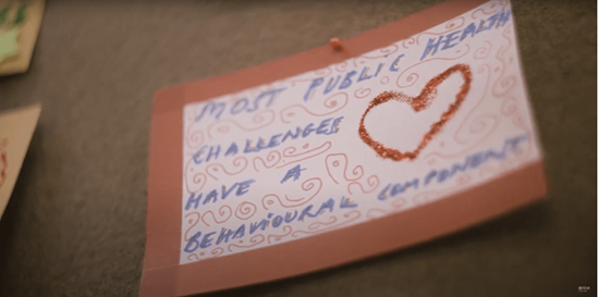 Card pinned on a cork board: "Most public health challenges have a behavioural component" and a heart