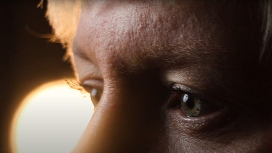 Close-up of a person's eyes looking ahead in soft, dramatic lighting, conveying a sense of focus and emotion