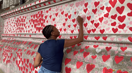 A woman writing on The National Covid Memorial Wall in London, United Kingdom.