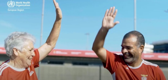 Smiling players in red shirts high-five each other on a sunny day.